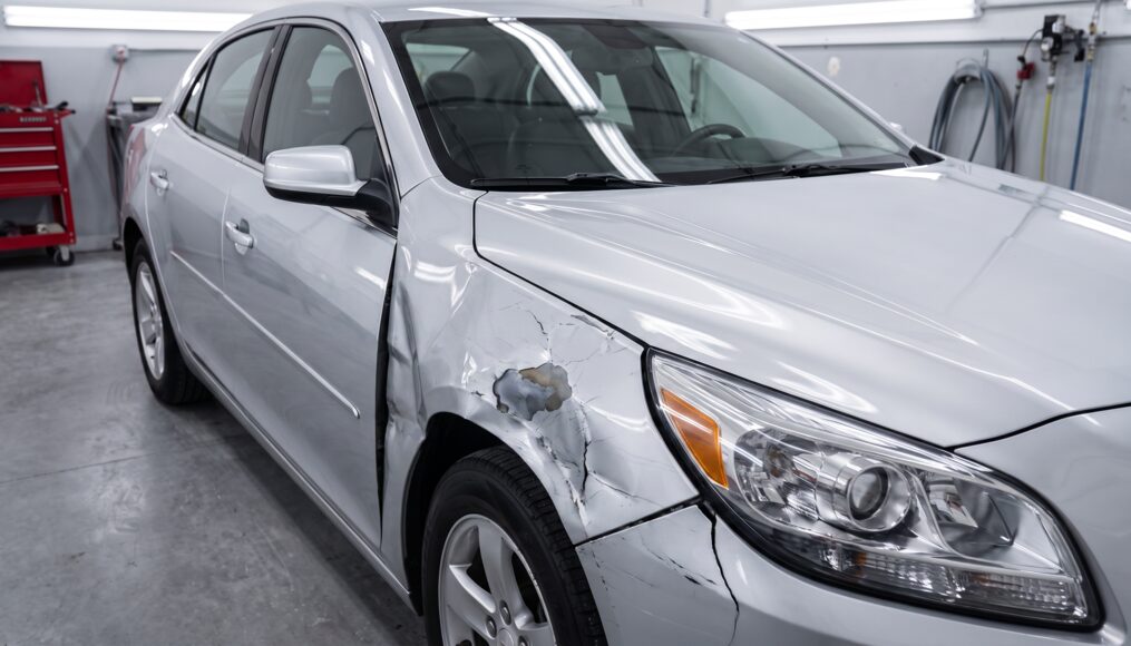 Sedan front fender with collision damage, creased metal and cracked paint, before repair