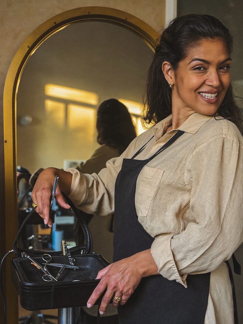 Mireille Foss standing beside her styling chair, shears in hand