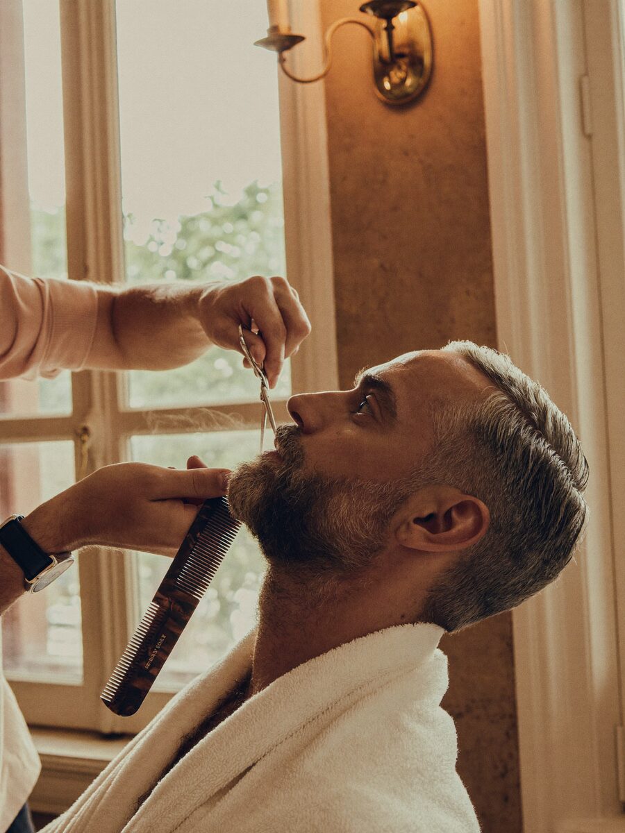 The finishing detail of a classic scissor cut and beard trim, barber's comb in frame