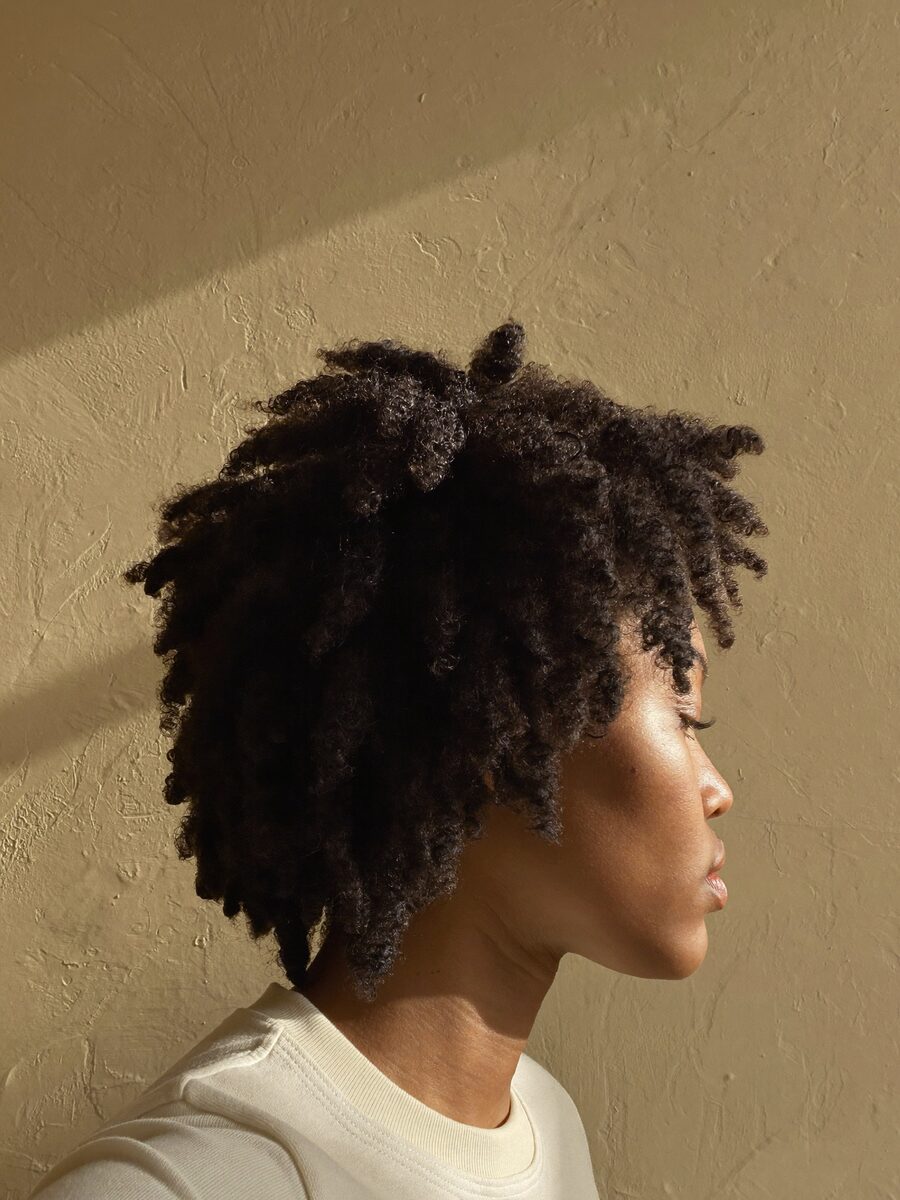 A tapered natural afro shaped and defined, photographed in profile with the light behind